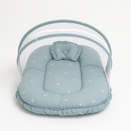 Blue baby bed with white heart print, pillow, and protective mosquito net canopy

